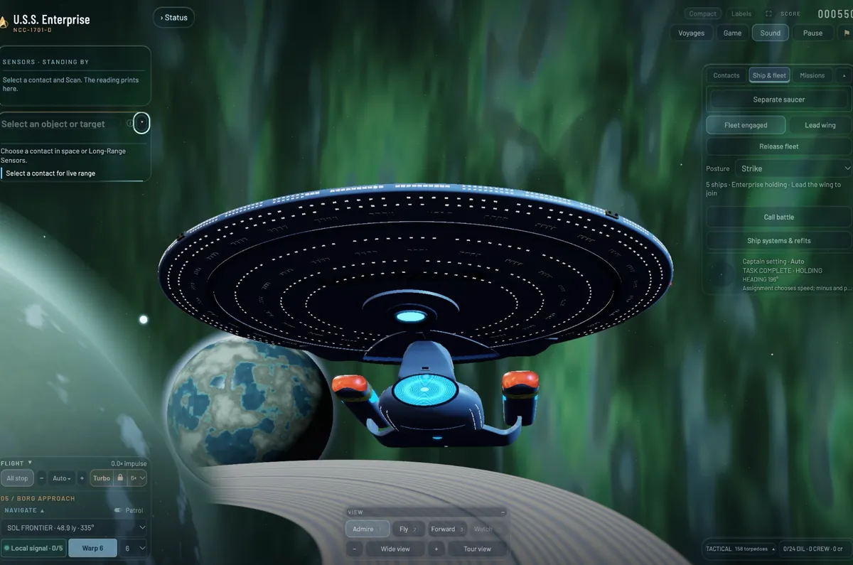 The Enterprise head-on from just below, the deflector dish glowing blue, above a planet's rings in a green nebula.