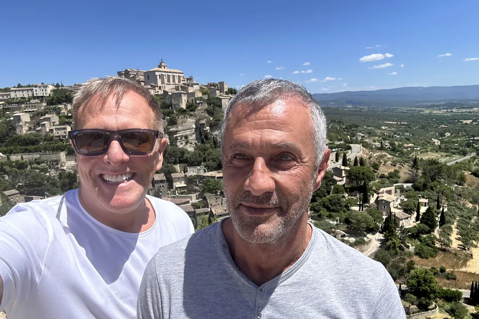 Eric with a friend, the hill village of Gordes behind them, in 2024.