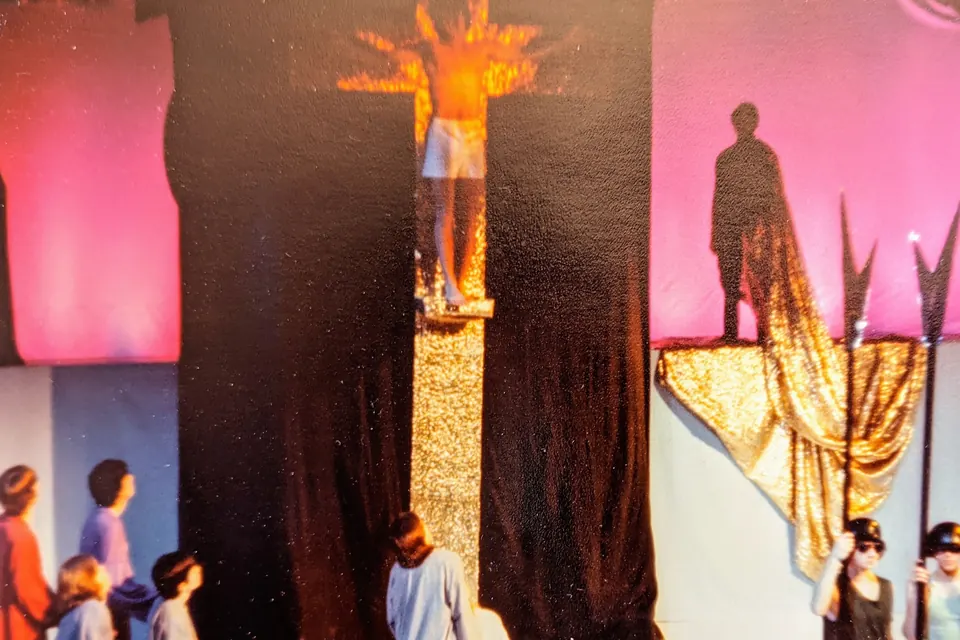 Jesus Christ Superstar at Exeter: Eric as Jesus on the cross, lit gold, with soldiers and apostles below.