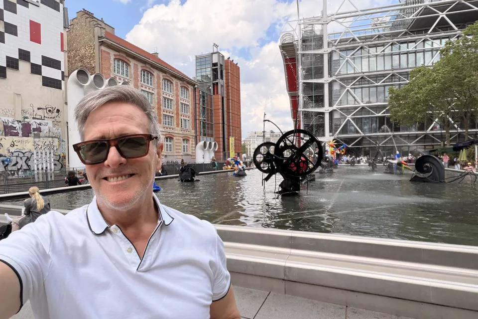 Eric smiling beside the Stravinsky Fountain, the Centre Pompidou behind him.